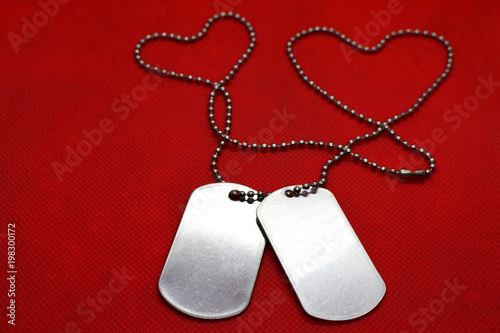 Two blank silver color soldier military tags on ball chain on bright red background with copy space for text. Love concept.