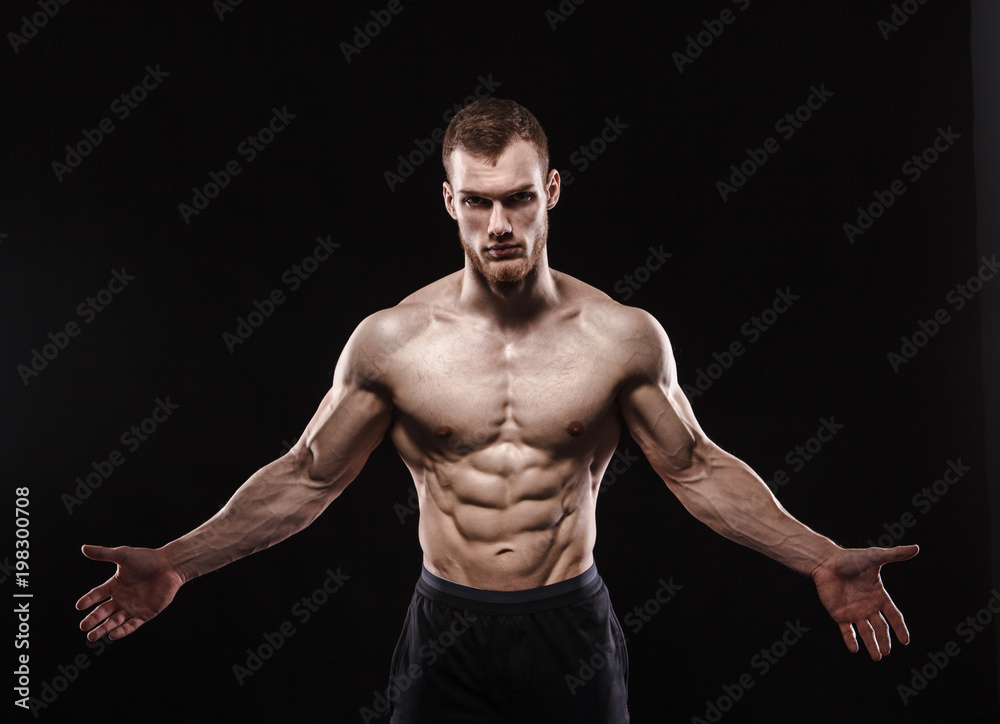 Aggressive man is a fighter, a bodybuilder with a naked torso on a black