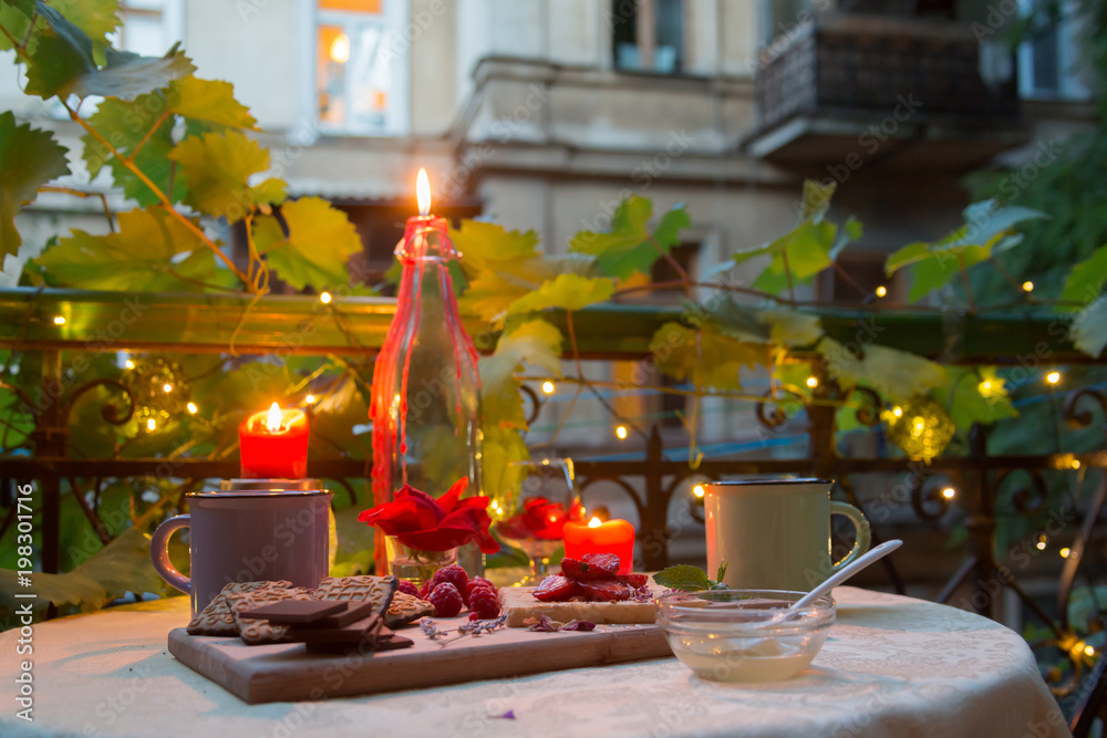 Romantic dinner table on balcony with candles, chocolates and fruits