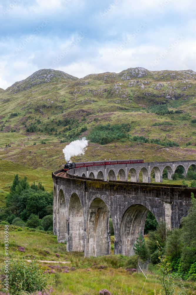 Jacobite Steam Train Locomotive passing Glenfinnan Viaduct, the famous location appears on the films