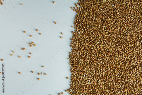 Buckwheat is evenly scattered on a white table.