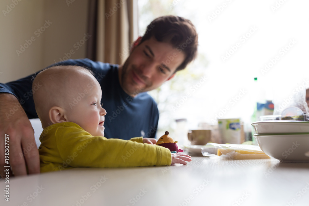 Father caring his baby boy at breakfast table