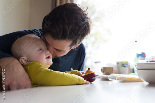 Young father playing with baby boy at breakfast table