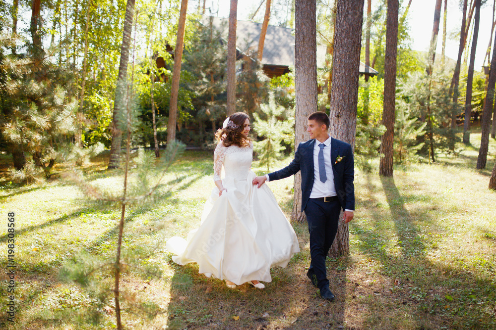 Couple of newlyweds at wedding in nature. Bride and groom on walk in green forest