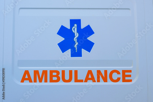 Photograph of ambulance car sign and text on white. The emergency services "Star of Life"