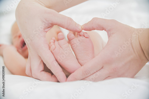 the feet of the baby in the hands of mother closeup