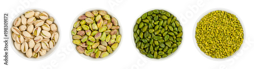 Pistachios in white porcelain bowls. Roasted pistachio seeds in shells and shelled. Green, dried fruits, whole and chopped. Pistacia vera. Isolated food photo close up from above on white background.