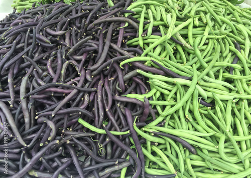purple and green beans piled in a market display