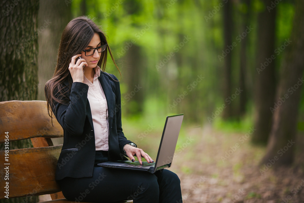 brunette with glasses and with a laptop talking on the phone brunette with glasses and with a laptop talking on the phone