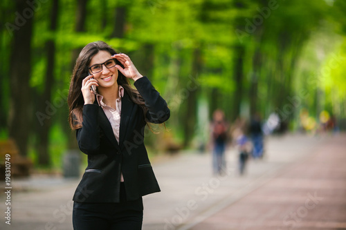 business woman is walking in the park and talking on the phone photo