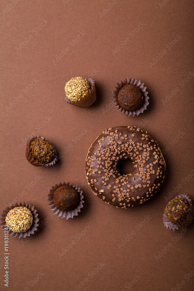 Chocolate donuts with chocolate truffles on brown background. Monochromatic concept. Chocolate donuts with chocolate truffles on brown background. Monochromatic concept.