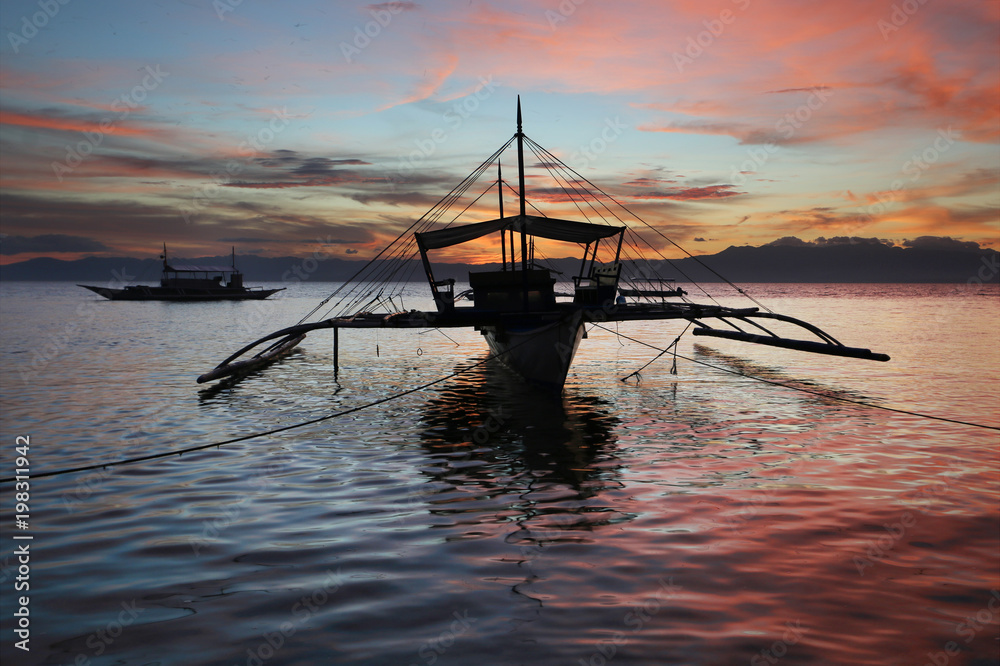 Amazing colorfull sunset at the sea with philippine boats.