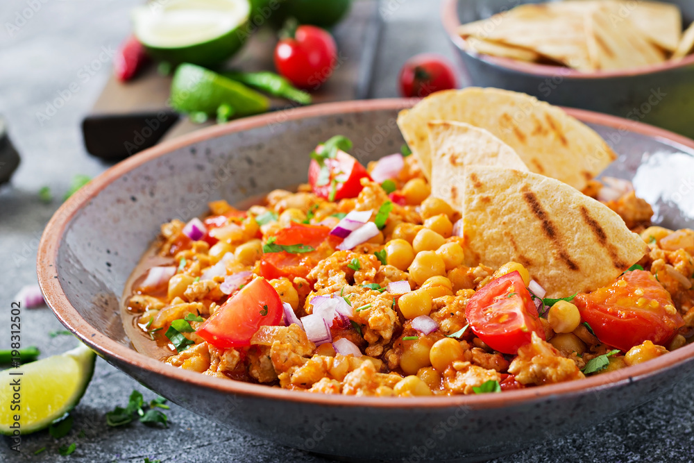 Chili con carne of turkey with chickpeas served with nachos. Chili with meat, nachos, lime, hot pepper. Mexican / Texas traditional food. Chili con carne of turkey with chickpeas served with nachos. Chili with meat, nachos, lime, hot pepper. Mexican / Texas traditional food.