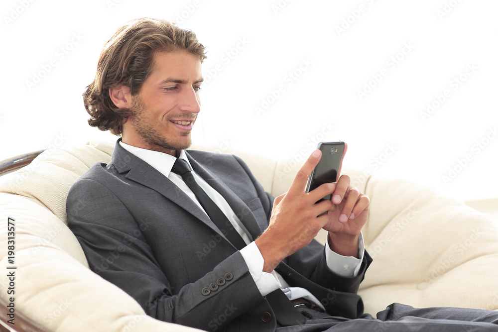 successful business man with a smartphone sitting in a comfortable chair successful business man with a smartphone sitting in a comfortable chair
