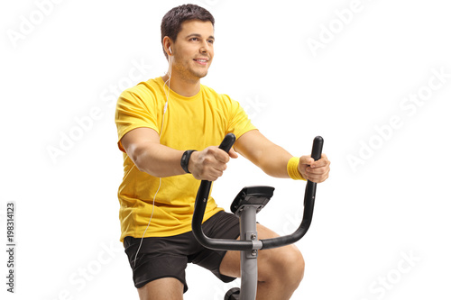 Young guy with headphones exercising on a stationary bike