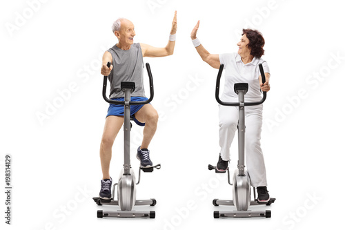 Seniors on exercise bikes high-fiving each other