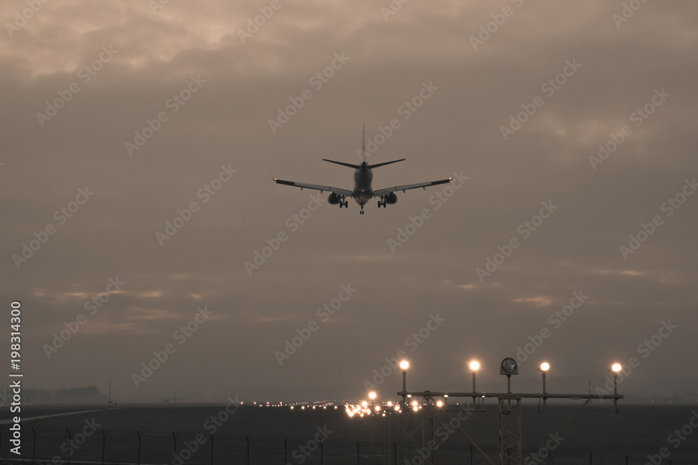 A passenger plane is landing on the background of the twilight, photo in retro style