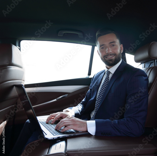 Businessman working on laptop keyboard sitting in car