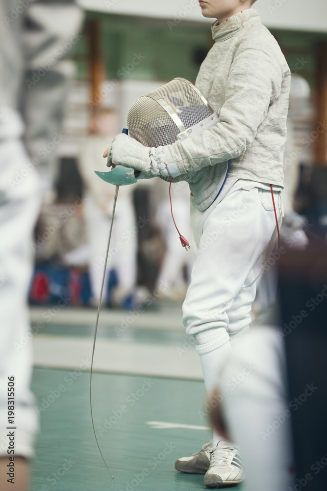 Young fencer holding rapier in his hand on the fencing tournament