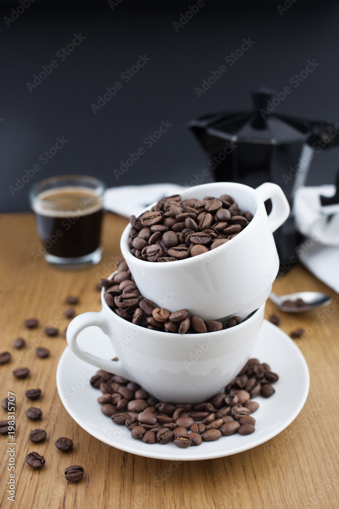 Espresso shot, coffee beans in the cup and coffee percolator on wooden table with black background Espresso shot, coffee beans in the cup and coffee percolator on wooden table with black background