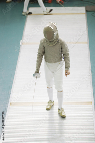 Boy teenager fencer in special costume at the fencing competition with rapier