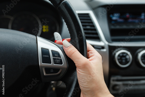 Close-up of woman's hand holding a steering wheel. Girl driver rides behind the wheel of a large car or SUV. © korchemkin