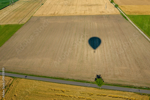 Cień balonu lecącego nad polami z widokiem na horyzont.
