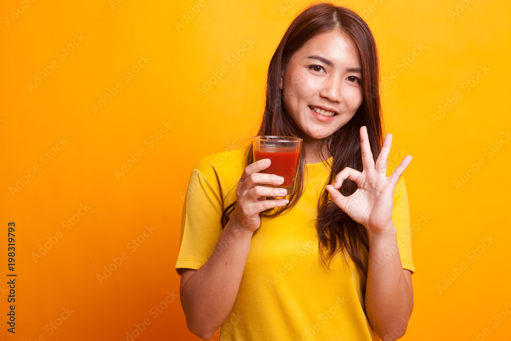 Young Asian woman show OK with tomato juice in yellow dress Young Asian woman show OK with tomato juice in yellow dress