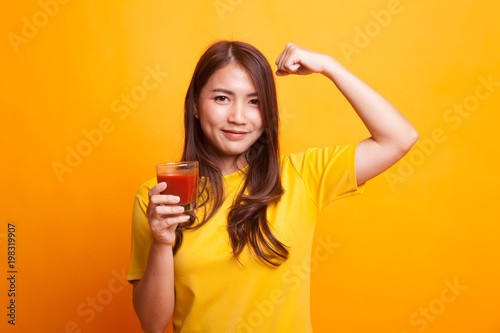 Strong healthy Asian woman with tomato juice in yellow dress