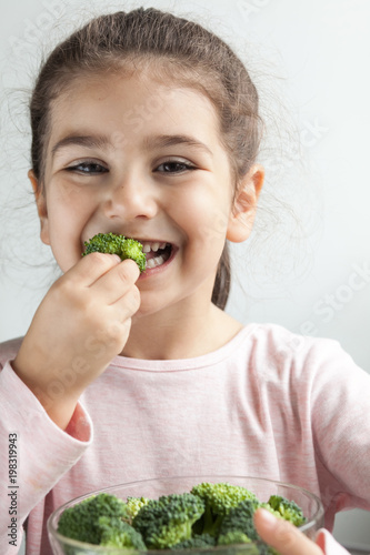 Happy smiling child girl eating vegetables. Healthy food.