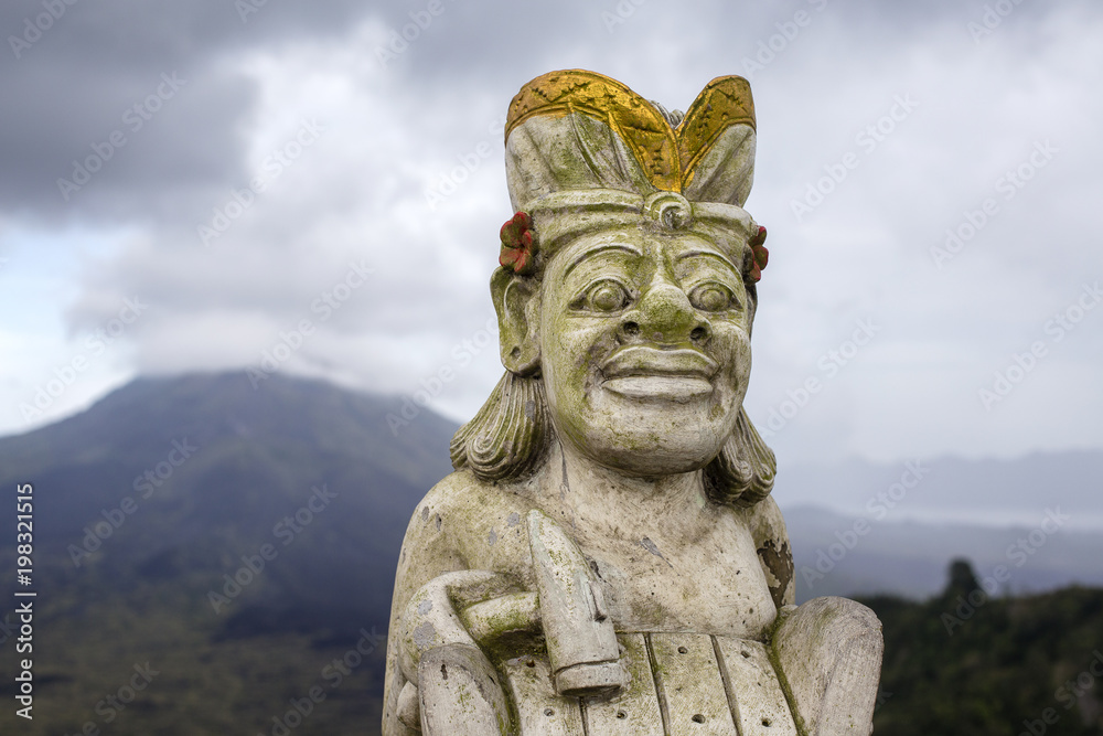 Traditional Balinese sculpture against the background of the volcano Batur. Island Bali, Indonesia