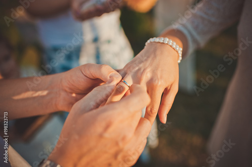 Wedding ceremony with bride and groom putting golden rings on each other fingers