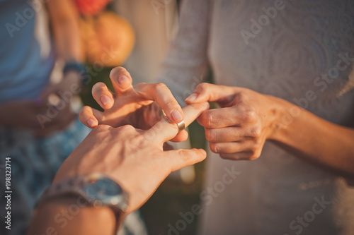 Wedding ceremony with bride and groom putting golden rings on each other fingers