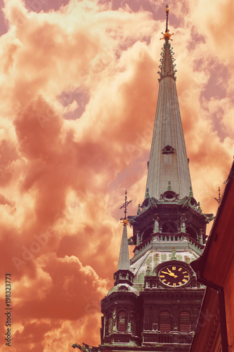 Spire of German Church located in Old Town (Gamla Stan) of Stockholm, Sweden agaisn a drama red sky (toned) photo