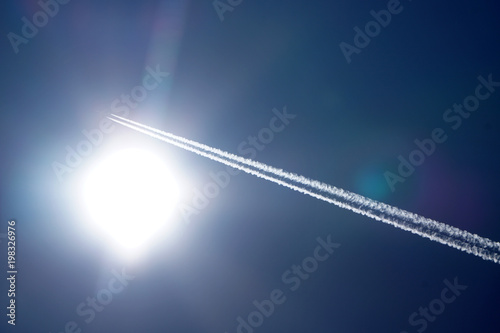 Airplane trails tracks chemtrails in the deep blue sky photo