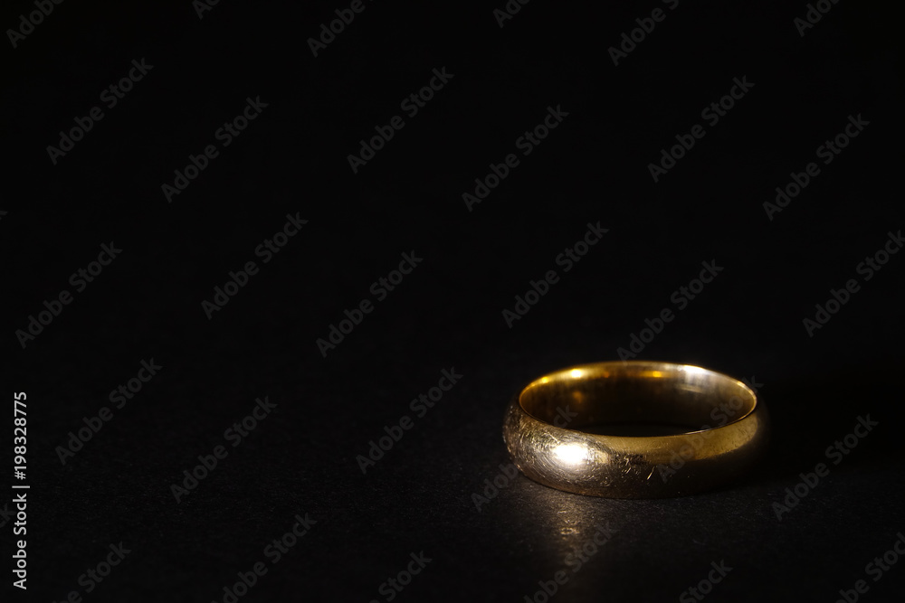 A scratched used old gold wedding ring on black background. Copyspace for text. A scratched used old gold wedding ring on black background. Copyspace for text.