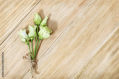 Small delicate flowers of eustoma on a wooden surface. Small bouquet on aged wood table.