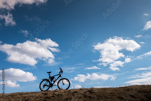 Fototapeta Naklejka Na Ścianę i Meble -  Bike silhouette in blue sky with clouds. symbol of independence and freedom