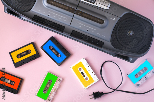 Old black retro cassette music audio tape recorder and retro cassette tape collection on pink background
