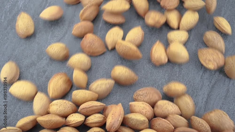 Almonds on gray stone background, slow motion, top view Almonds on gray stone background, slow motion, top view