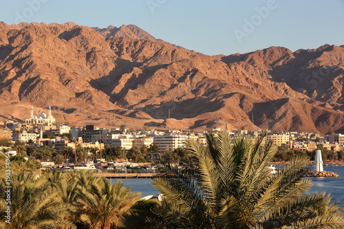 General view of the town of Aqaba at sunset with Palm trees in the foreground and mountains in the background, Jordan, Middle East photo