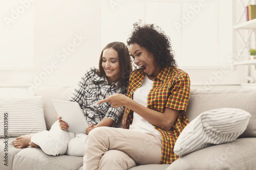 Two happy female friends using tablet. © Prostock-studio