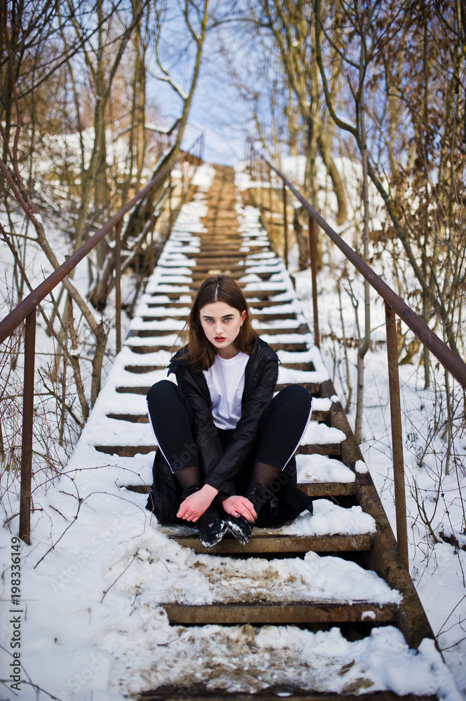 Fototapeta premium Fashionable long legs brunette model in long black cloak posed outdoor at winter day.