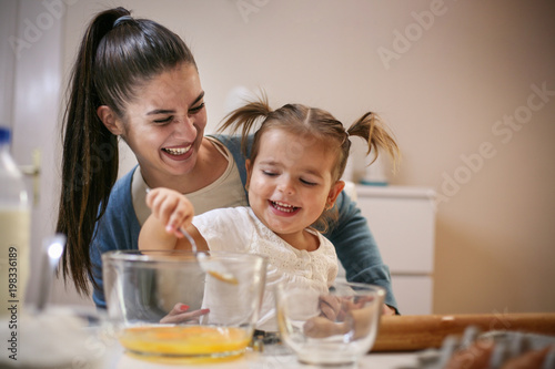 Mother and smiling girl baking cookie together.