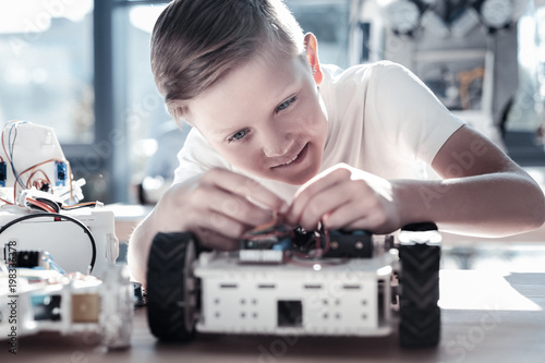 This is so interesting. Selective focus on a focused preteen boy focusing his attention on a robotic machine while enjoying the process of working on a school technological process.