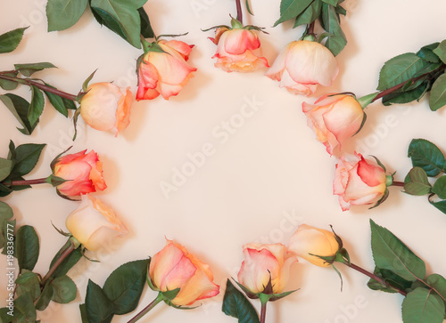 Floral round frame made of pink roses on beige background. Flat lay, top view.