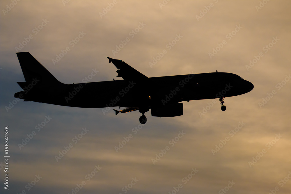 Silhouette passenger airplane flying away in to sky high altitude on sunset Silhouette passenger airplane flying away in to sky high altitude on sunset