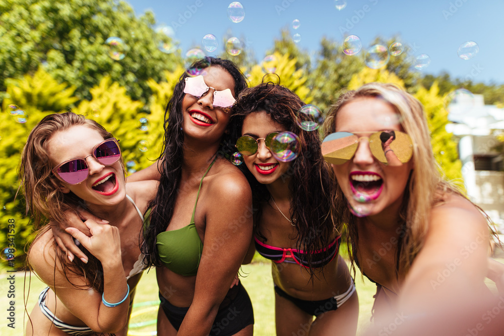 Cheerful friends taking selfie at the poolside Cheerful friends taking selfie at the poolside