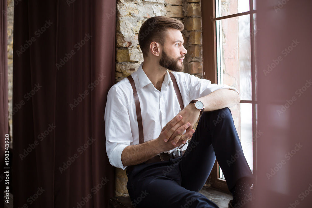 Close up portrait of handsome smiling bearded man in white shirt, guy looking on the window.