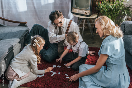 Photos happy family with two children playing dominoes together at home, 1950s